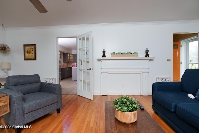 living area featuring ornamental molding, wood finished floors, a ceiling fan, and baseboards