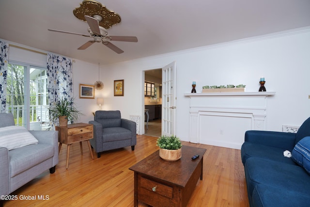 living room with light wood-style flooring, ceiling fan, and ornamental molding