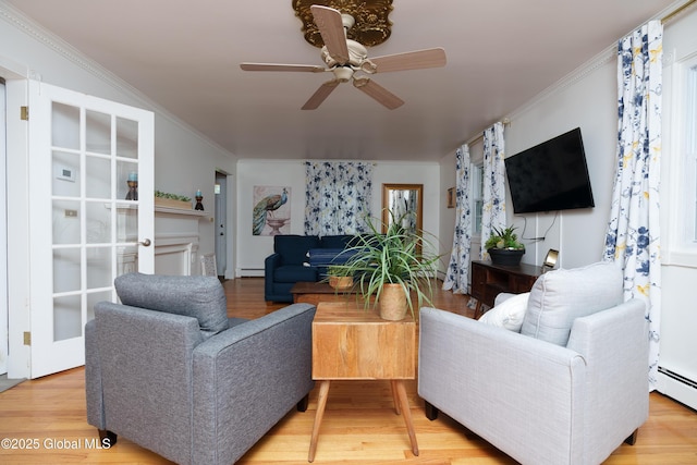 living area featuring a ceiling fan, a baseboard heating unit, light wood-style floors, and ornamental molding