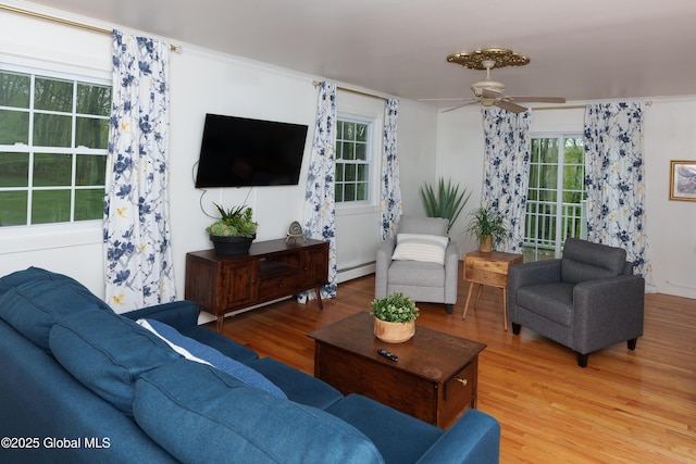 living area with light wood finished floors, a baseboard radiator, and a ceiling fan