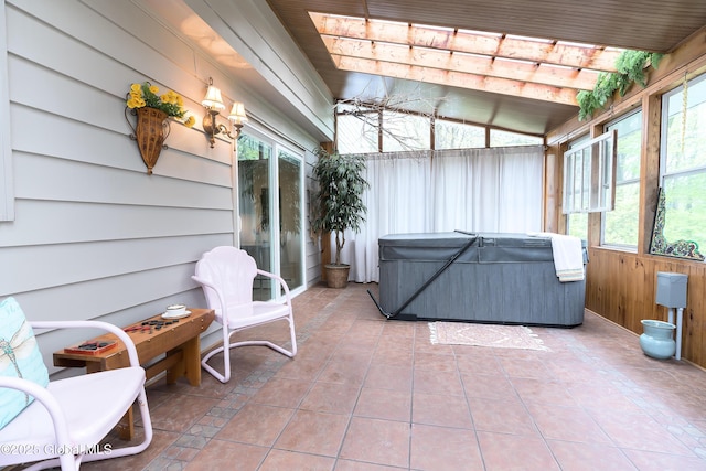 sunroom with a hot tub, wooden walls, tile patterned flooring, and lofted ceiling
