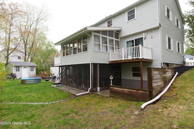 rear view of house with a sunroom, a yard, and an outdoor structure