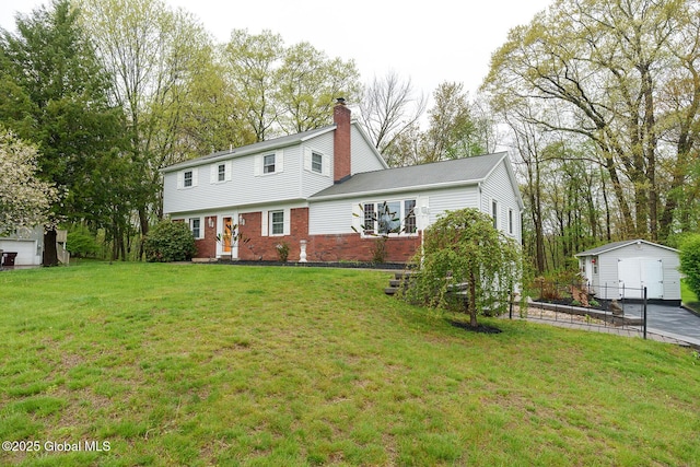 back of property with brick siding, a chimney, an outbuilding, and a yard