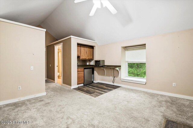 11 Cotton Ct, Bolton, NY 12824 - kitchen with dark colored carpet, lofted ceiling, dark countertops, ceiling fan, and brown cabinetry