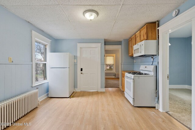 1108 Cutler St, Schenectady, NY 12303 - kitchen with light wood finished floors, radiator, brown cabinetry, baseboards, and white appliances