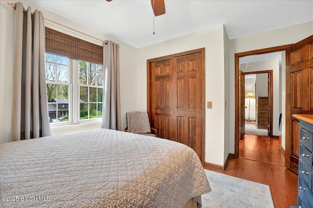 bedroom with a closet, a ceiling fan, wood finished floors, and baseboards
