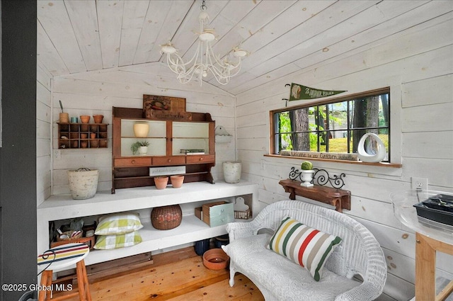 interior space featuring lofted ceiling, a notable chandelier, wood ceiling, wooden walls, and hardwood / wood-style flooring