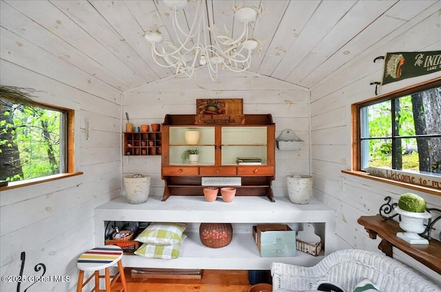 dining space with lofted ceiling, wooden walls, an inviting chandelier, and wooden ceiling