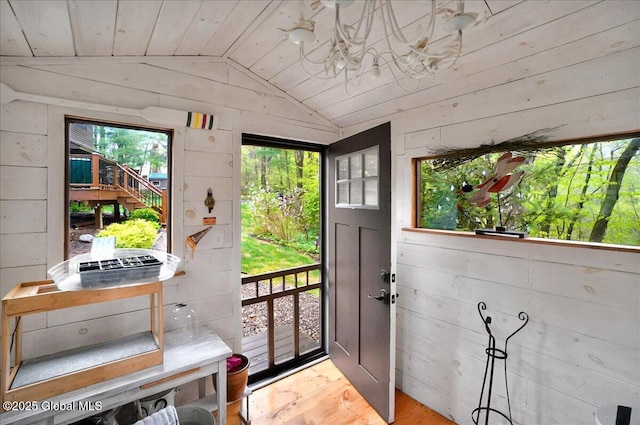 doorway featuring vaulted ceiling, wooden walls, wood ceiling, and wood finished floors