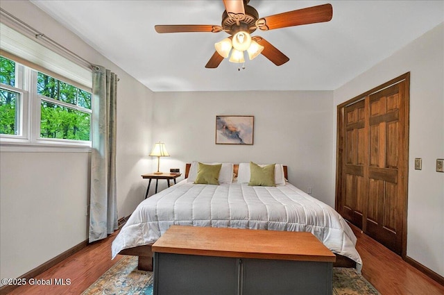 bedroom with a ceiling fan, wood finished floors, and baseboards
