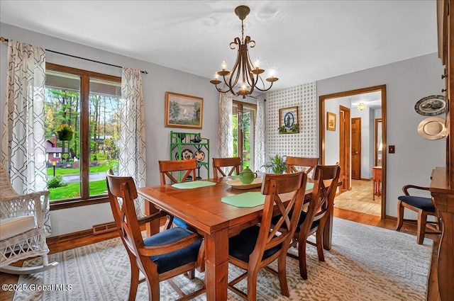 dining area with light wood-type flooring, baseboards, and a notable chandelier