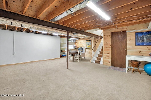 unfinished basement featuring stairway, wooden walls, and carpet floors