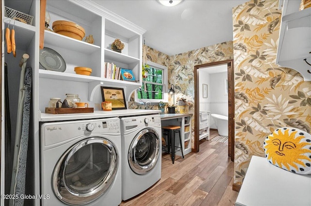 clothes washing area with light wood finished floors, wallpapered walls, laundry area, and washing machine and clothes dryer