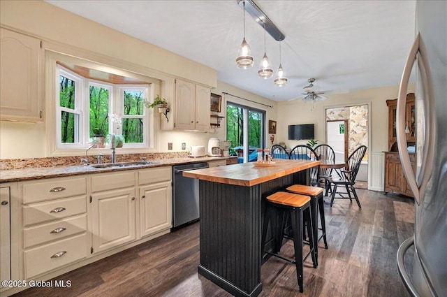 kitchen with a breakfast bar, a sink, stainless steel appliances, dark wood finished floors, and butcher block counters