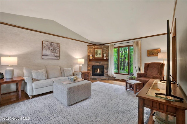 living area featuring wood finished floors, lofted ceiling, and a stone fireplace