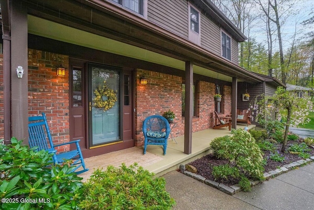 entrance to property featuring brick siding and covered porch