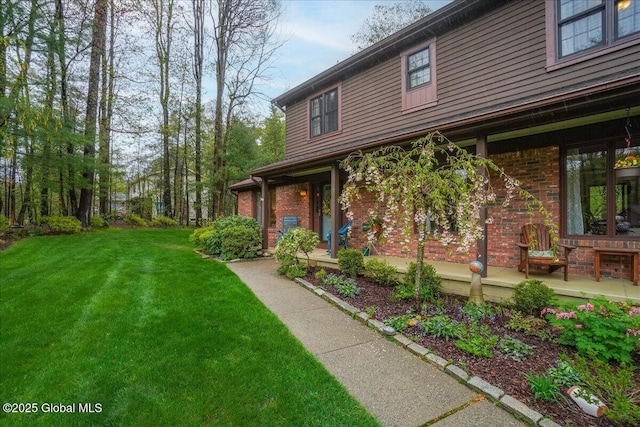 exterior space featuring brick siding and a front yard
