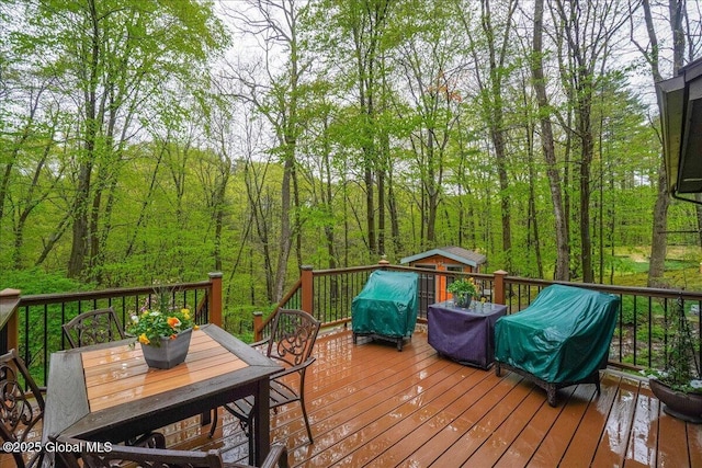 deck featuring area for grilling, a forest view, and outdoor dining space