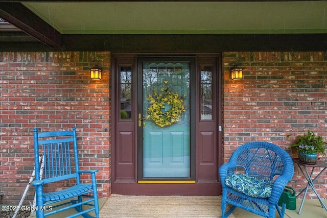 doorway to property with covered porch and brick siding