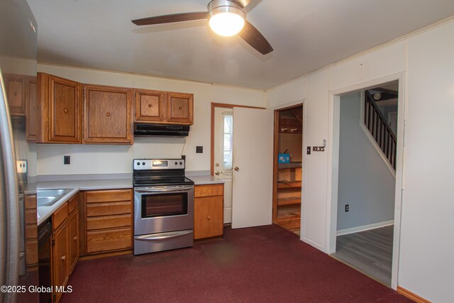 kitchen featuring electric range, under cabinet range hood, brown cabinetry, a ceiling fan, and light countertops