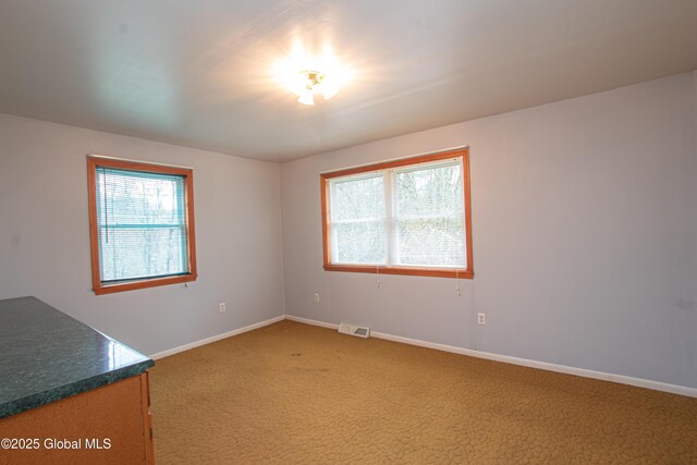 unfurnished room featuring light carpet, plenty of natural light, and baseboards