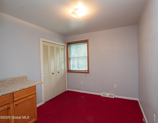 unfurnished bedroom with a closet, baseboards, and dark colored carpet