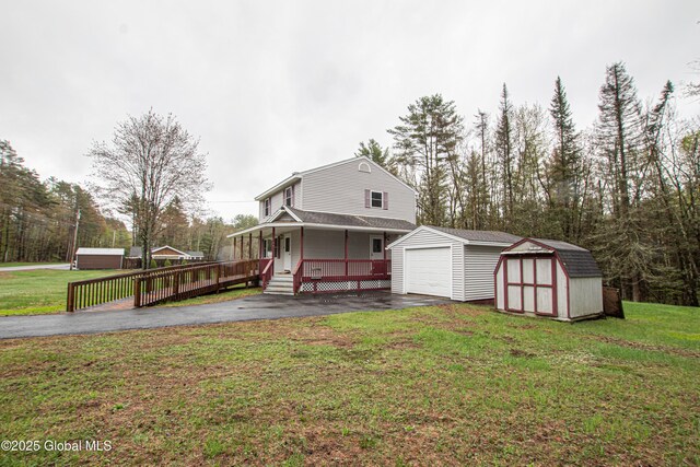 view of front of house featuring a storage unit, an outbuilding, asphalt driveway, and a porch