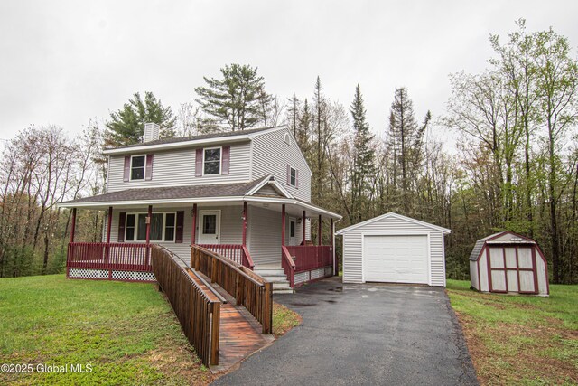 farmhouse-style home with an outdoor structure, a porch, driveway, a chimney, and a detached garage