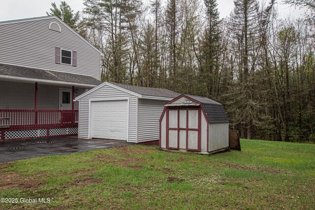 detached garage with driveway and a storage shed