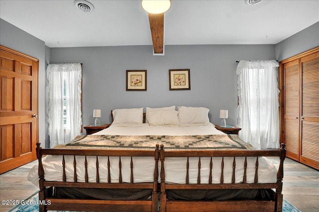 bedroom featuring light wood-type flooring, a closet, and beam ceiling