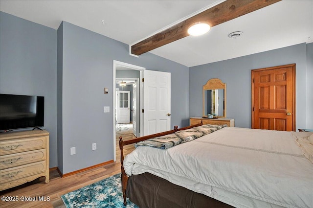 bedroom featuring beamed ceiling, wood finished floors, and baseboards
