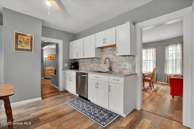 kitchen with a sink, stainless steel dishwasher, light countertops, light wood-type flooring, and a ceiling fan