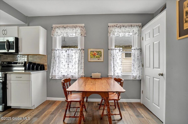 dining room with wood finished floors, plenty of natural light, and baseboards