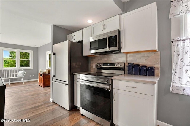 kitchen featuring stainless steel appliances, baseboards, white cabinets, light wood finished floors, and light countertops