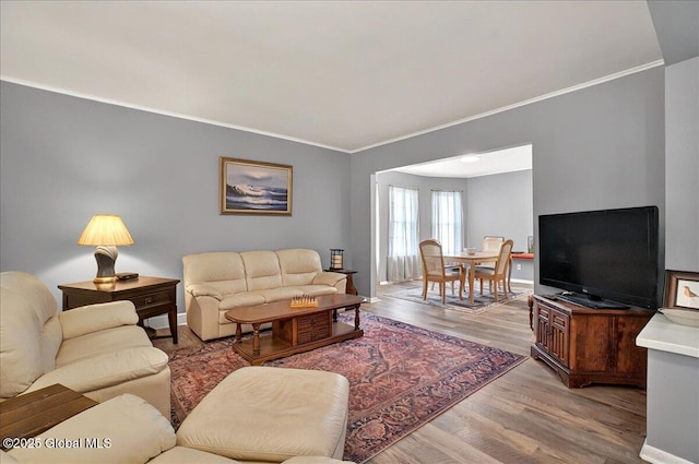 living room featuring crown molding, light wood-style flooring, and baseboards