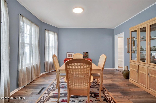 dining space featuring crown molding, wood finished floors, and baseboards