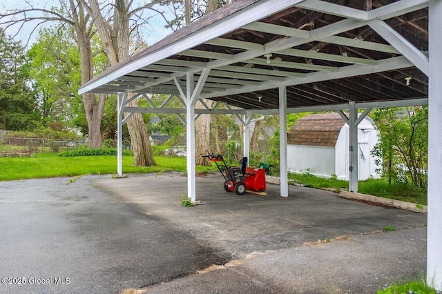 view of vehicle parking featuring a storage unit and a carport