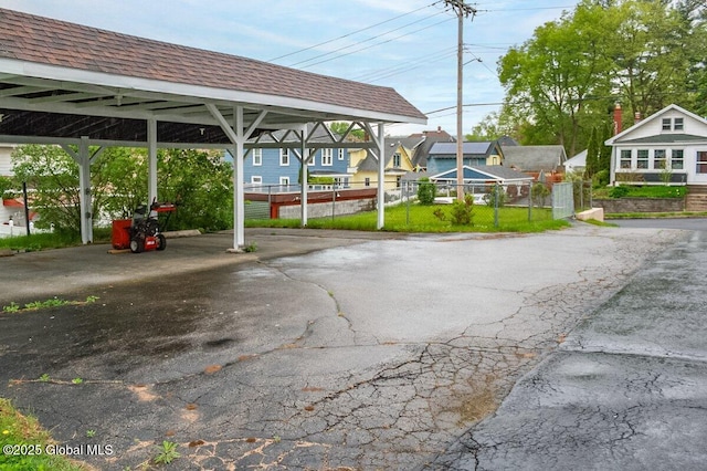 view of vehicle parking featuring a carport, asphalt driveway, and fence