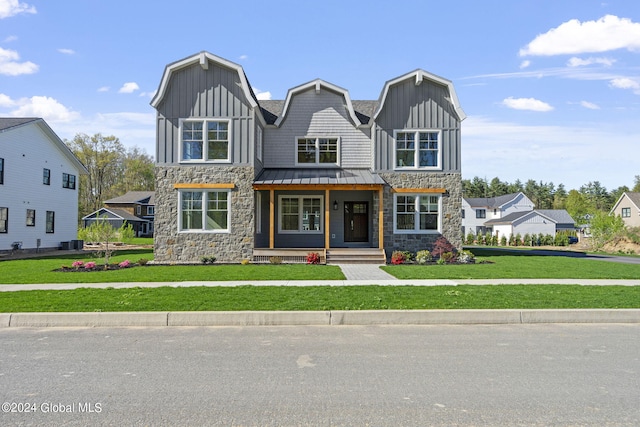 view of front of property with stone siding, a front lawn, board and batten siding, and a standing seam roof