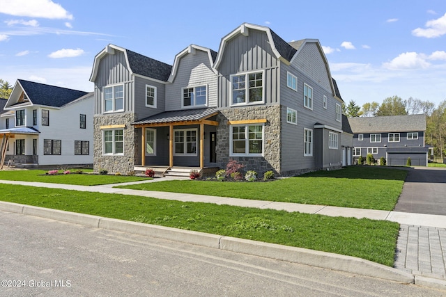 view of front of property with stone siding, board and batten siding, covered porch, and a front lawn