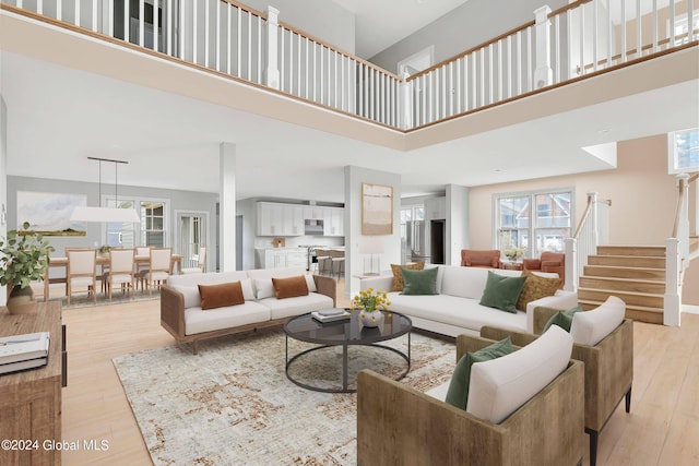 living area featuring a high ceiling, light wood finished floors, and stairway