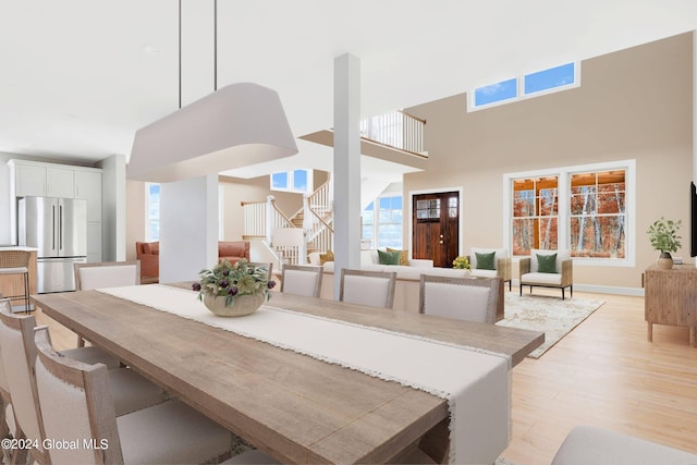 dining area with plenty of natural light, stairway, light wood-style flooring, and a towering ceiling