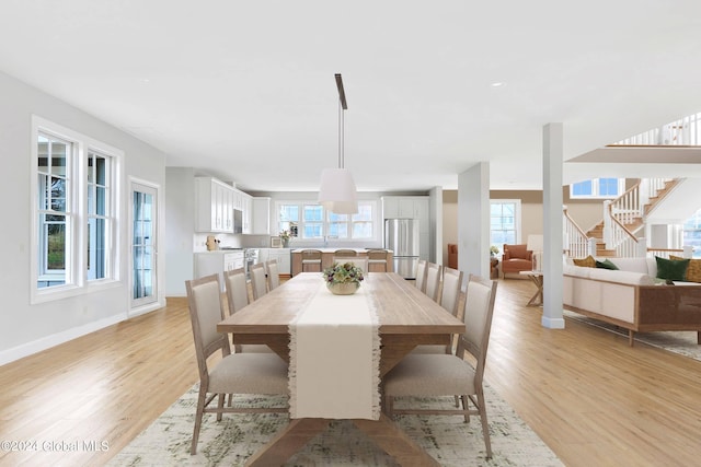 dining room with light wood-type flooring, stairway, and baseboards