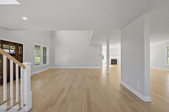unfurnished living room featuring light wood-type flooring, baseboards, a fireplace, recessed lighting, and stairs