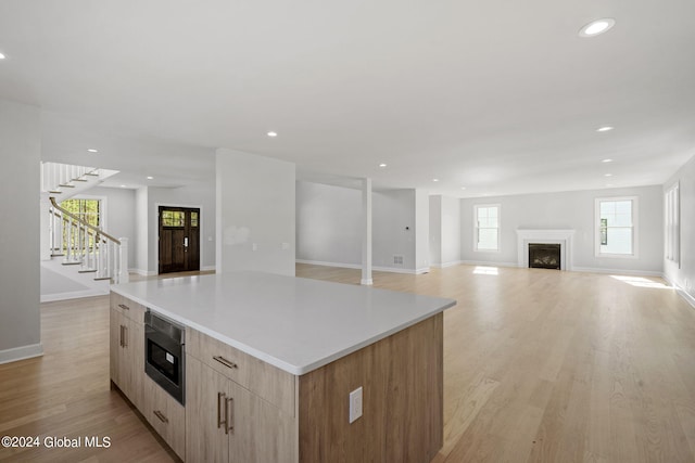 kitchen with built in microwave, open floor plan, a kitchen island, modern cabinets, and light brown cabinets