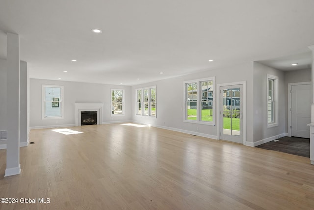 unfurnished living room featuring recessed lighting, baseboards, wood finished floors, and a fireplace