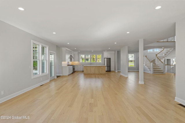 unfurnished living room with baseboards, recessed lighting, light wood-type flooring, and stairs