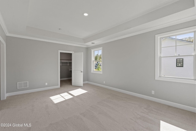 unfurnished bedroom with a tray ceiling, light colored carpet, baseboards, recessed lighting, and ornamental molding