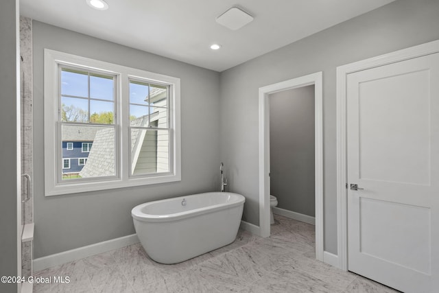 full bath with baseboards, toilet, a soaking tub, marble finish flooring, and recessed lighting