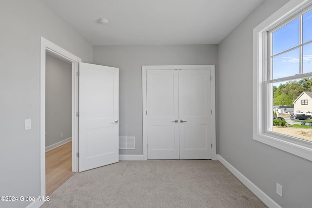 unfurnished bedroom with light colored carpet, baseboards, and a closet